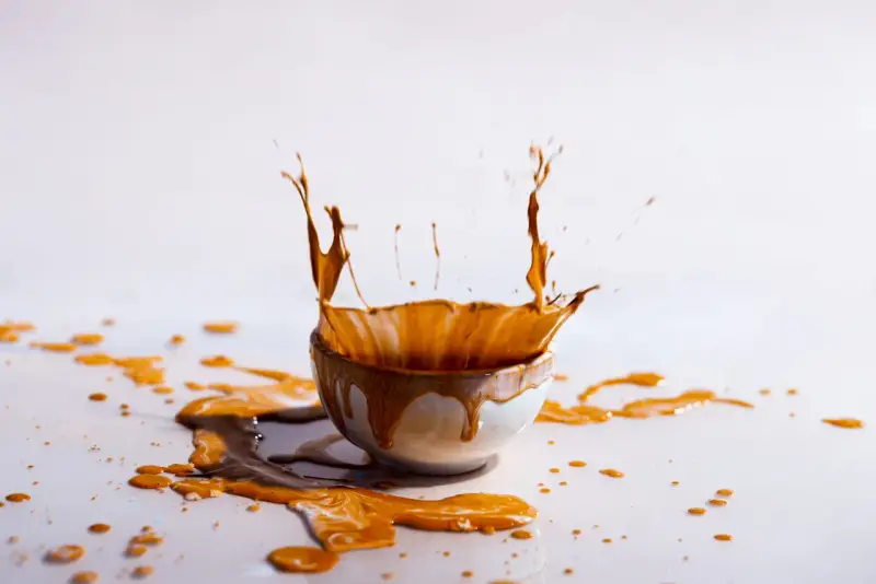 Schizzo di liquido marrone da una ciotola, creando macchie marroni sui vestiti dopo lavaggio in lavatrice.